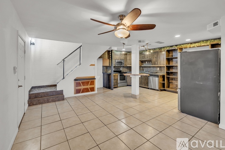 A spacious room with a ceiling fan and a staircase on the left side.