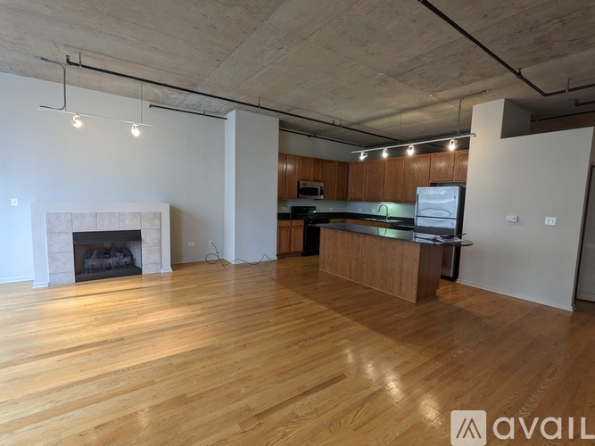 A spacious room with wooden floors and a fireplace.