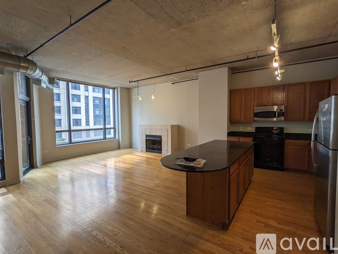 A spacious kitchen and living room with wooden floors and a large window.