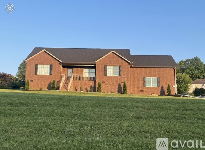 A large red brick house with a green lawn in front.