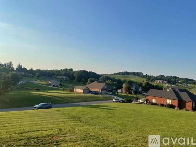 A car is parked on a grassy area in front of a house.