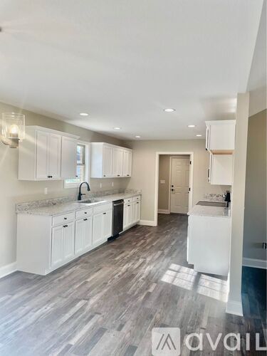A modern kitchen with white cabinets and a marble countertop.