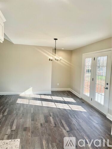 A room with wooden flooring and a chandelier.
