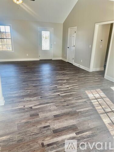 A room with wooden flooring and white walls.