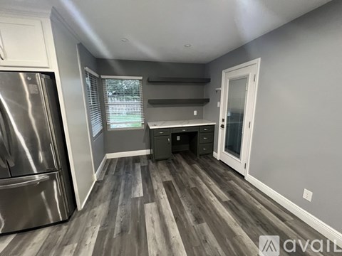 A kitchen with a stainless steel refrigerator and wooden flooring.