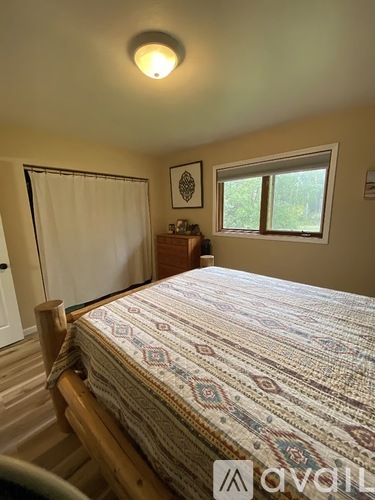 A bedroom with a bed, a window, and a wooden nightstand.
