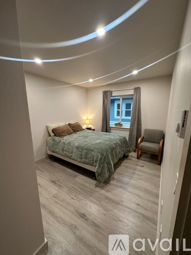 A bedroom with a bed, chair, and window.