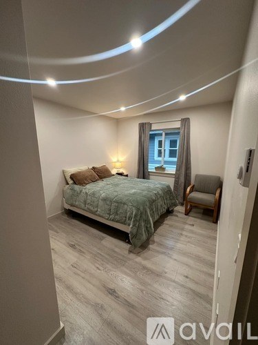 A bedroom with a bed, chair, and window.