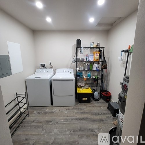 A small room with two washing machines and a shelf with various items.