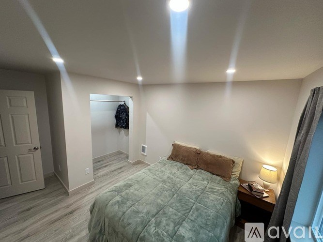 A bedroom with a bed, nightstand, and lamp.