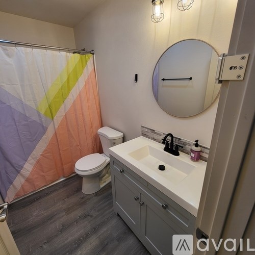 A bathroom with a toilet, sink, and shower curtain.