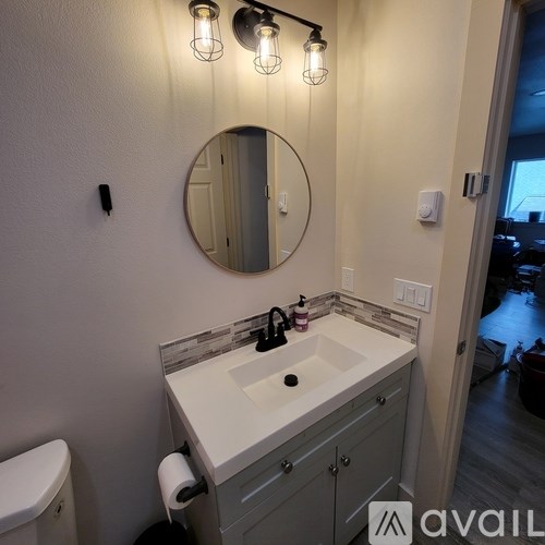 A bathroom with a sink, mirror, and lights.