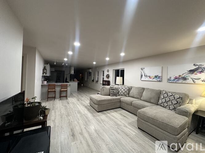 A living room with a grey couch and a piano.
