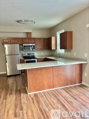 A kitchen with wooden cabinets and a stainless steel refrigerator.