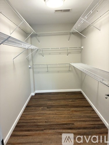 A room with white walls and wooden flooring, equipped with metal shelving.