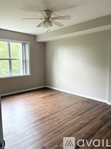 A room with a ceiling fan and wooden flooring.
