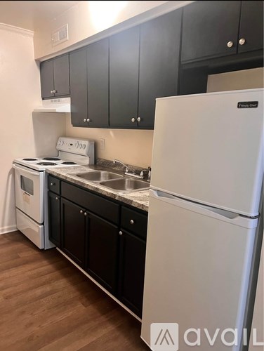 A kitchen with black cabinets and a white fridge.