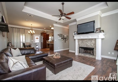 A living room with a brown leather couch and a white fireplace.