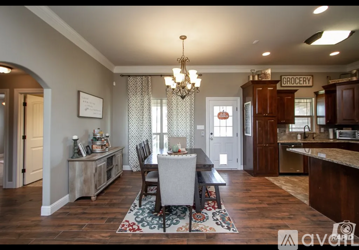 A dining room with a table set for four and a chandelier hanging from the ceiling.
