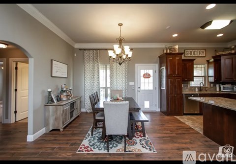 A dining room with a table set for four and a chandelier hanging from the ceiling.