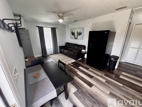 A living room with a black couch and a wooden floor.