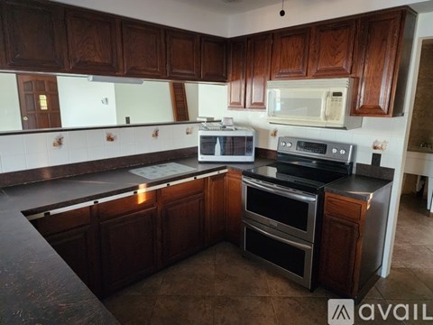 A kitchen with dark wood cabinets and black countertops.