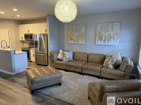 A modern living room with a brown leather couch and a grey ottoman.
