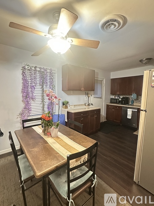 A kitchen with a table and chairs in the foreground and a refrigerator in the background.