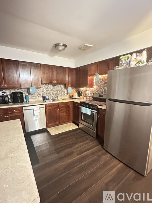 A kitchen with wooden cabinets and a stainless steel refrigerator.