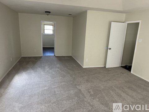 A spacious room with a carpeted floor and two doors, one of which is open.