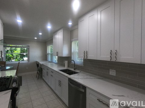 A kitchen with white cabinets and a marble countertop.