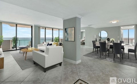 A living room with a white sofa and a dining table with chairs.