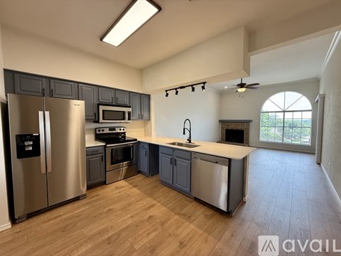 A kitchen with stainless steel appliances and wooden flooring.
