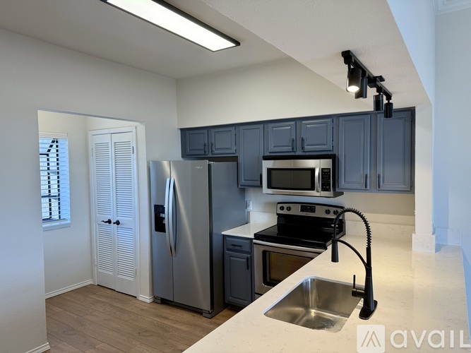 A kitchen with a refrigerator, microwave, oven, and sink.