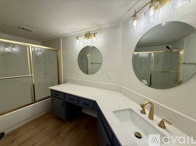 A bathroom with a white countertop and a sink with gold faucets.