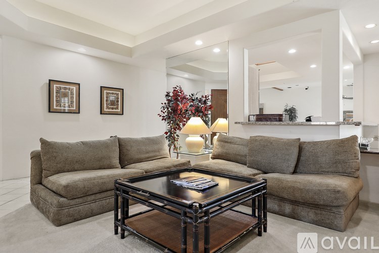 A living room with a glass coffee table and two couches.