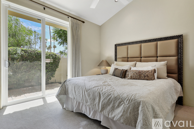 A bedroom with a large bed and a sliding glass door.