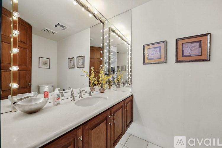 A bathroom with a vanity, a mirror, and a vase of flowers.