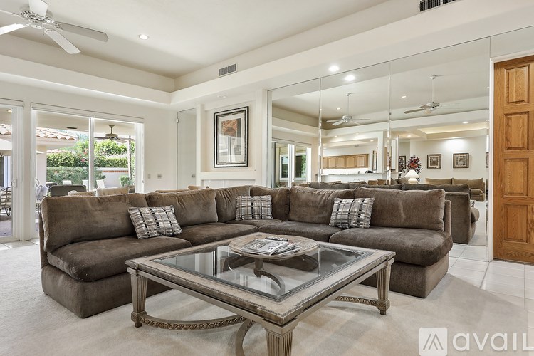 A spacious living room with a large sectional sofa and a glass coffee table.