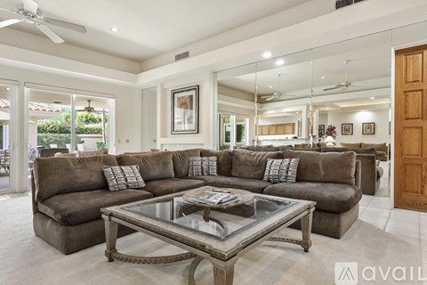A spacious living room with a large sectional sofa and a glass coffee table.
