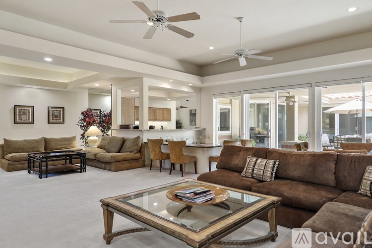 A living room with a glass coffee table and brown couches.