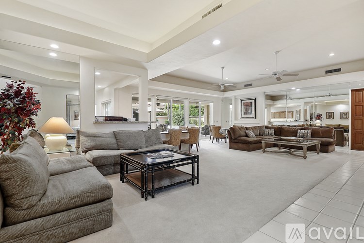 A living room with a variety of furniture including a grey sofa, a black coffee table, and a grey armchair.