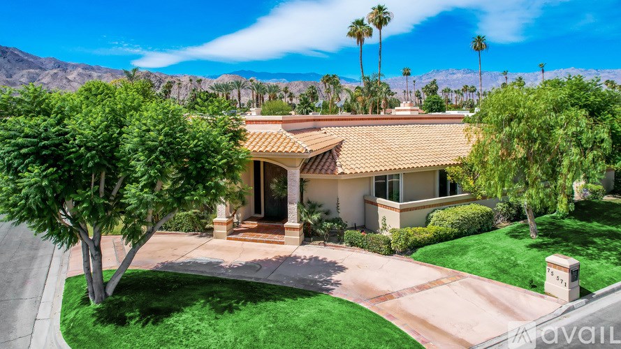 A house with a brown roof and a green lawn in front.