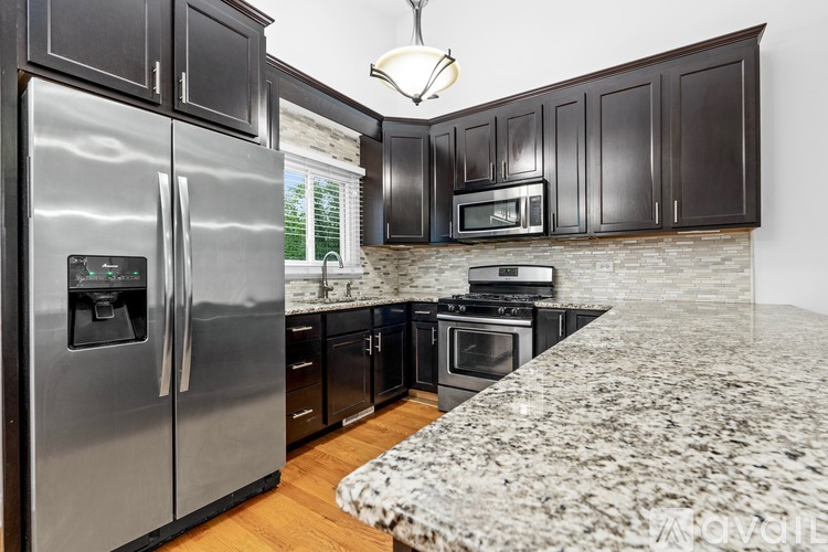 A kitchen with dark wood cabinets and a marble countertop.