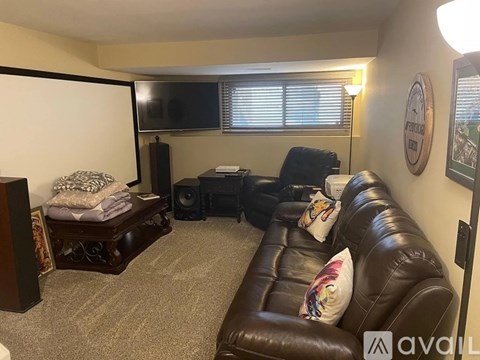 A living room with a brown leather couch and a flat screen TV mounted on the wall.