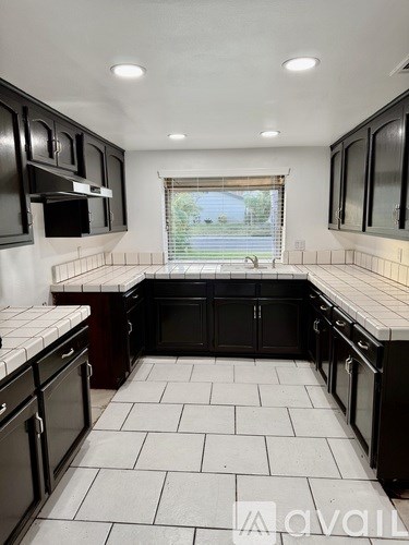 A kitchen with black cabinets and white tiled floors.
