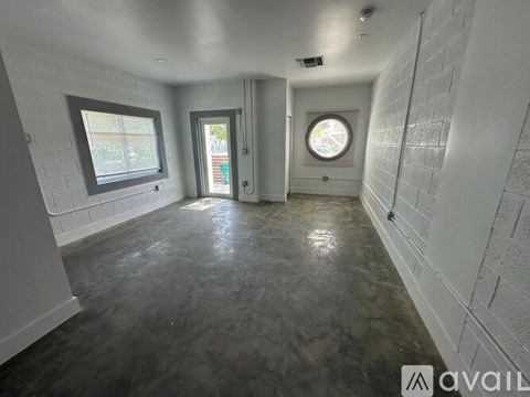 A spacious room with white walls and a grey floor.
