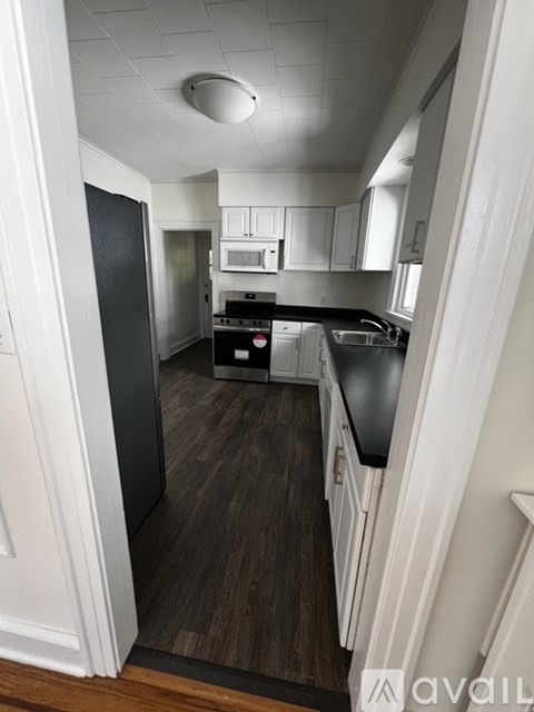 A kitchen with white cabinets and a black countertop.