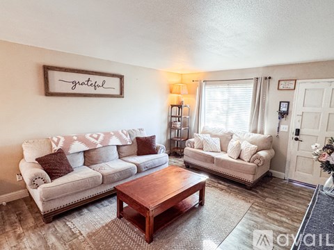A living room with a couch, a coffee table, and a "grateful" sign on the wall.