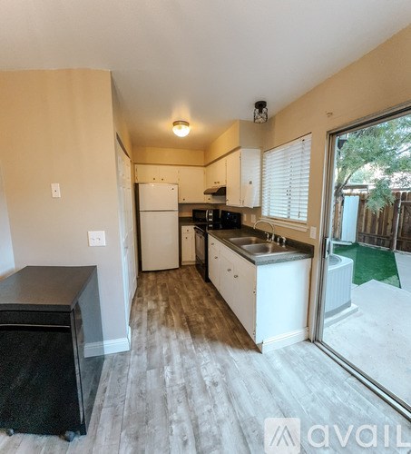 A kitchen with white appliances and a black dishwasher.